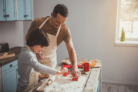 Man and child working with knead in kitchen. They cutting figurines from the dough. Copy space in right sideの写真素材