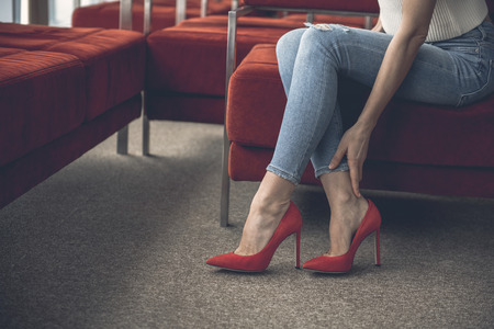 Close up female hand keeping leg while wearing high heel shoes. She feeling painの写真素材