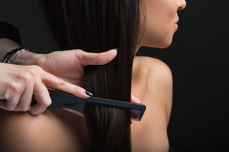 Haircare concept. Close up of hairdresser hands combing woman straight locksの写真素材