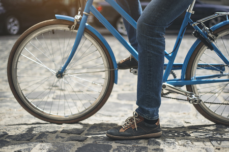 Close up of man legs starting riding bicycle on the road made of paving stoneの写真素材