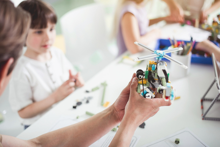 Close up man arm keeping toy from constructor. He showing it to interested kid during lesson. Contemporary technology conceptの写真素材