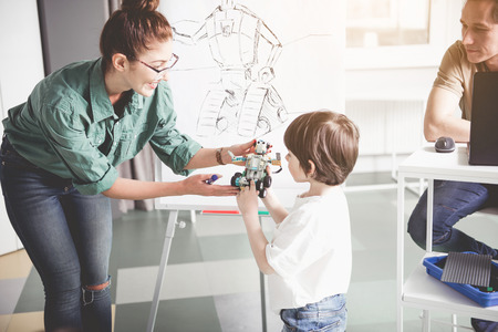Positive teacher giving modern robot happy kid. He telling information about it. Contemporary technology conceptの写真素材