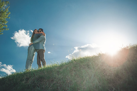 You are my everything. Low angle full length of attractive young people surrounded by colourful summer landscape and holding each other tightly. They are happy and calm. Copy space in right sideの写真素材
