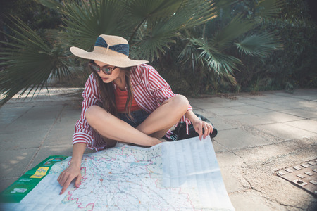 Here is my place of destination. Serious female tourist is pointing finger on map with concentration. Woman is resting on path outdoorの写真素材