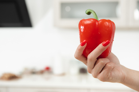Ready for cooking. Close up of woman hand holding red pepper. Copy space in left side の写真素材