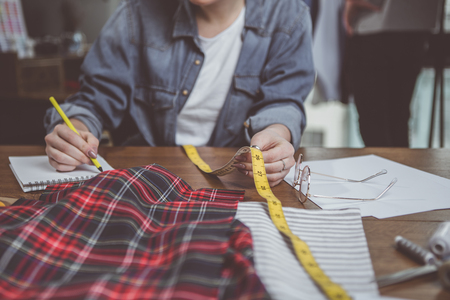 Close up female hands holding long ruler while making notes. She sitting at tableの写真素材