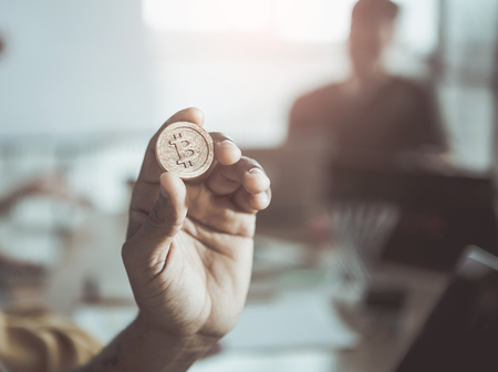 Close-up selective focus of hand is demonstrating bitcoin. Most important cryptocurrency concept. Blurred background with people. Copy space in the right sideの写真素材