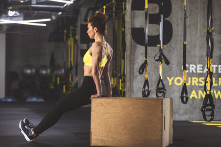 Full length side view orderly girl working out with box in fitness centerの写真素材