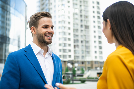 Portrait of excited businessman listening to his colleague with interest. He is standing on street and laughingの写真素材