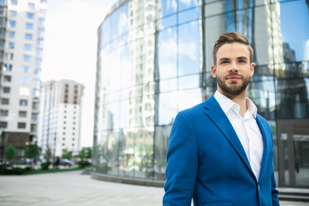 Waist up portrait of successful businessman resting after work outdoor in city. He is looking forward pensively. Copy spaceの写真素材