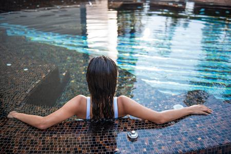 Young lady with wet hair locating in water during rest in hot sunny day. She turning back to cameraの写真素材