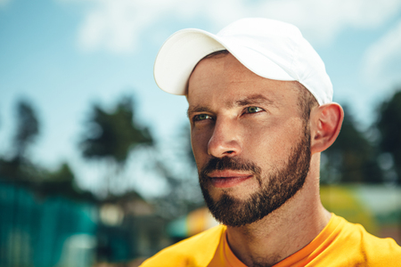 Portrait of satisfied bearded male athlete wearing cap while locating outdoor. Copy spaceの写真素材