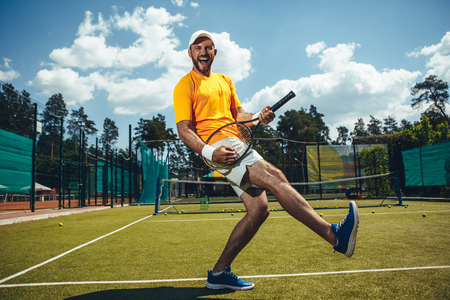 Full length portrait of cheerful man imaging he playing guitar on sport equipment on courtの写真素材