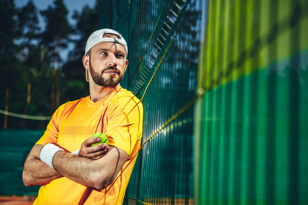 Portrait of outgoing male athlete holding sport equipment in hand while looking away. He resting after good training outdoorの写真素材