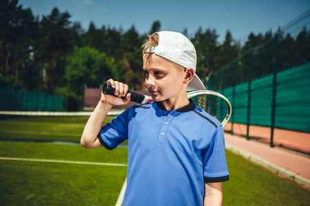 Pensive child holding sport tool in hand during game on contemporary courtの写真素材