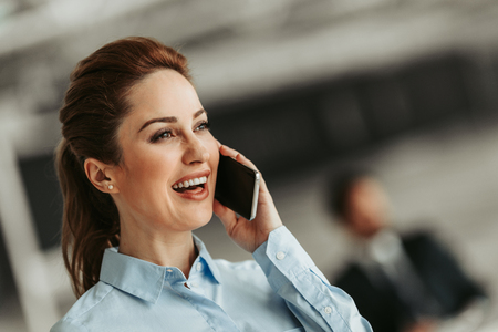 Portrait of laughing woman talking on phone during job. Glad businesswoman during communication conceptの写真素材