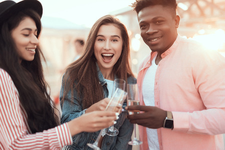 Portrait of happy man and cheerful females enjoying glasses of champagne during partyの写真素材