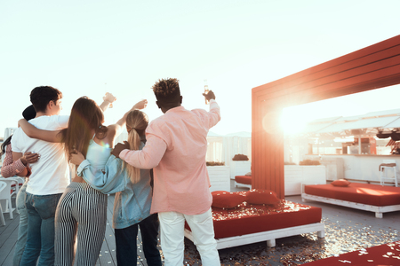 Cheers. Pretty women with long hair and males gesticulating arms while tasting beverage. They turning back to camera. Unity conceptの写真素材
