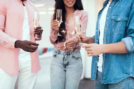 Smiling lady and male comrades keeping bengal light while drinking delicious champagneの写真素材