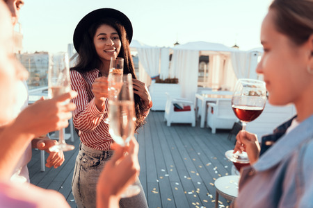 Cheers. Positive girls tasting beverage while communicating during party outdoor
