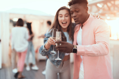 Portrait of smiling male and cheerful woman clanging alcohol beverage while embracing during partyの写真素材