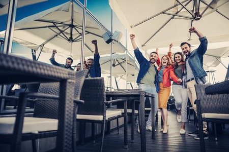 Happiness. Full length portrait of cheerful company celebrating success. They making victory gesture and looking at camera with wide smilesの写真素材
