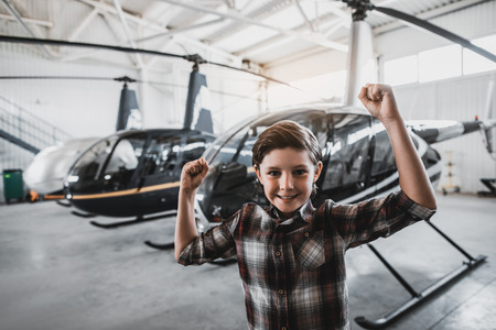 Portrait of pleased boy gesticulating hands while looking at camera. He locating at exhibition of rotorcraftsの写真素材