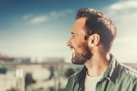 Feeling happy. Close up side view of handsome guy looking away and smiling. Copy space in left sideの写真素材