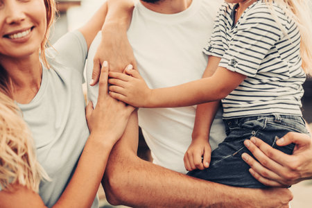 Positive lady embracing husband. He keeping little child in arms. Glad parents and kid expressing unity and love conceptの写真素材