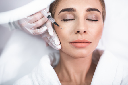 Clean skin. Close up portrait of attractive young lady with closed eyes. Girl getting injection in cheekの写真素材