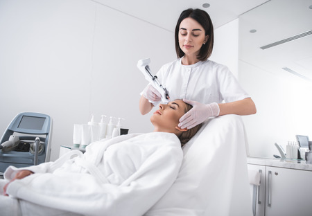 Skincare for you. Attractive young woman laying on daybed at cosmetologist cabinet while having...