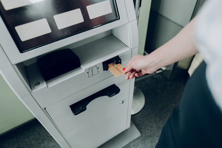 Inserting plastic card. Top view of female hand is holding plastic card into ATM machine at airportの写真素材