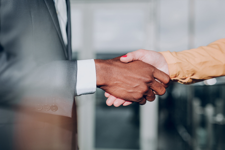 Deal. Close up of handshake of two business partners. Male and female shaking hands on a strong noteの写真素材