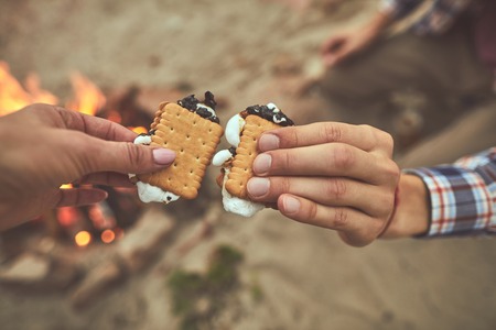 Bite and sup. Close up of people hands holding sweet cookies at the beach
