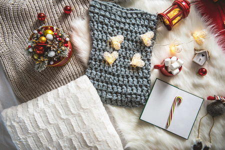 Top view knitted scarf, sketch-book, garland and cup with marshmallow locating on carpet. Winter holiday conceptの写真素材