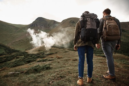 Morning in mountains. Couple of hikers enjoying spending time in the mountains and holding hands while walkingの写真素材