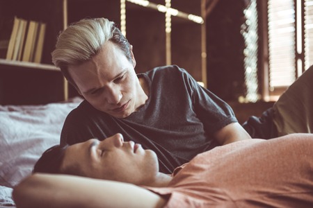 I adore you. Toned portrait of young man with dyed hair gazing at boyfriend while he sleeping with...