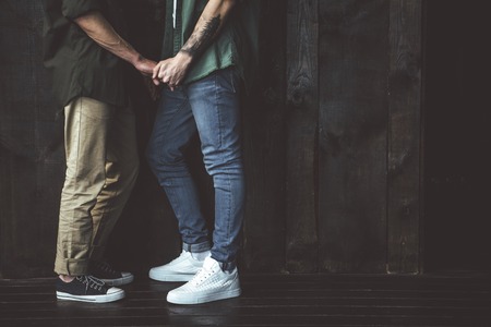 Sweet love. Cropped side view portrait of two loving man standing against the wooden wall