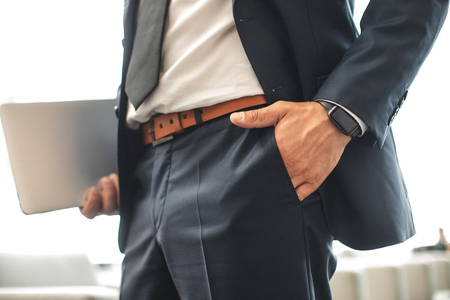 Confident man putting hand in pocket and holding documents in other one. Focus on male suitの写真素材