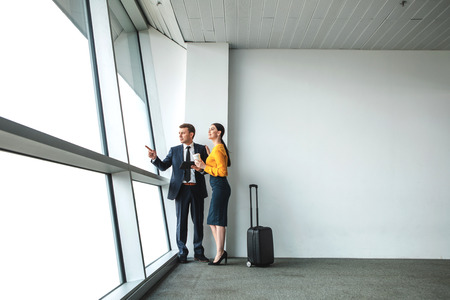 Business people in assignment. Man point aside and holding tablet while woman looking there. Copy space on right sideの写真素材