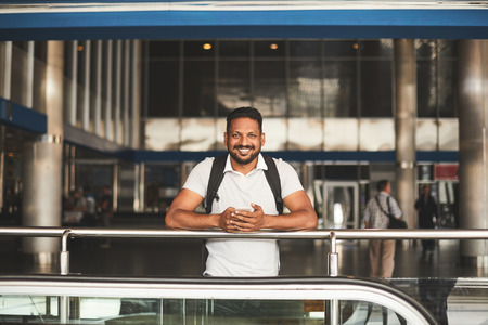 Cheerful smiling Hindu man waiting for his relatives at the railway station while leaning on the handrailの写真素材
