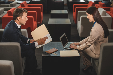 Working hard. Serious people are sitting in cafe and doing business task. She typing on laptopの写真素材