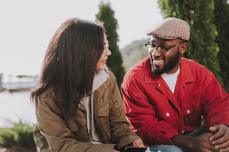 Positive young international couple having a pleasant talk while resting outdoorsの写真素材