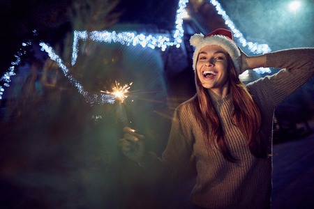 Joyful young smiling woman standing near her house while having fun during winter holidaysの写真素材
