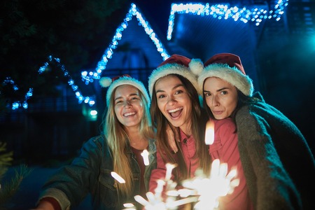 Delighted happy young women holding sparklers while enjoying winter timeの写真素材