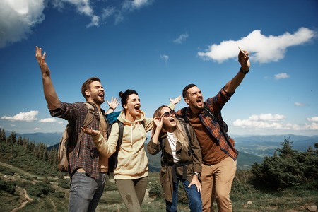 Two women and two men having fun during trip with rucksacks in highland.の写真素材