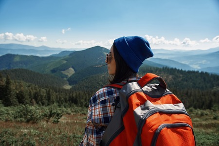 Tranquil woman is standing with rucksack while wearing sunglasses.の写真素材
