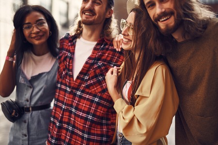 Friends hugging. Positive relaxed young people standing close to each other and smiling cheerfullyの写真素材