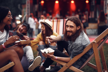 Portrait of cheerful hipster friends sitting on folding chairs and having fun.の写真素材