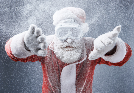 Looking for the way out. Waist up portrait of bearded old man in Santa costume getting stuck in the snowstormの写真素材
